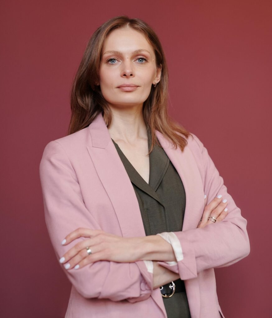 Elegant businesswoman with arms crossed in studio portrait, showcasing leadership and confidence.