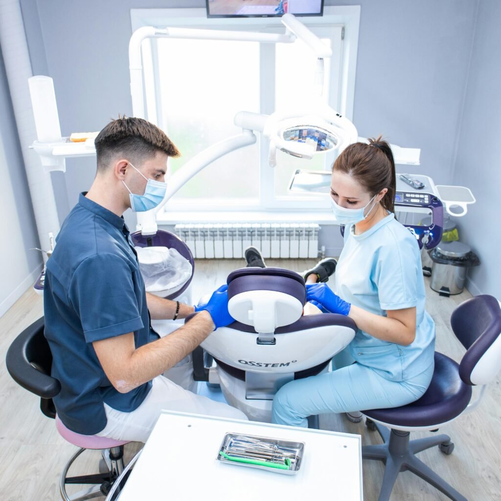 Dentist and assistant wearing masks working together in a modern clinic.